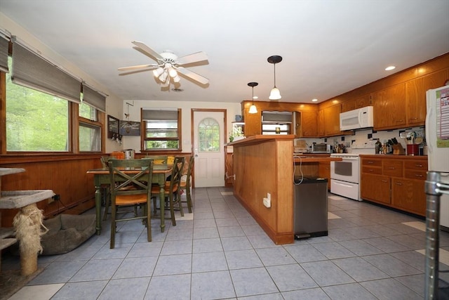 kitchen featuring a peninsula, white appliances, brown cabinets, ceiling fan, and light tile patterned floors