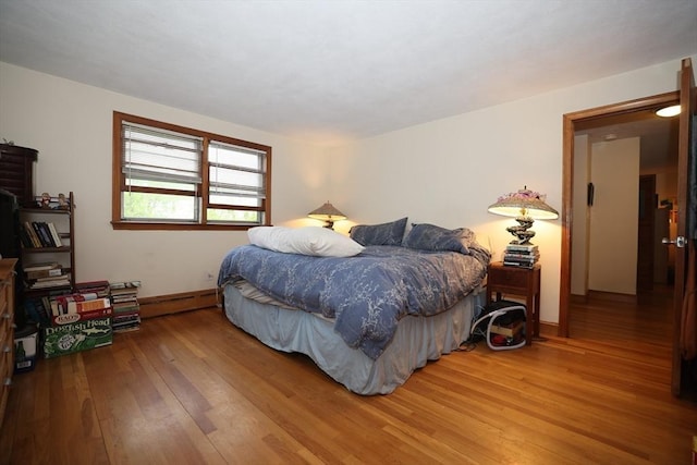bedroom with baseboards, hardwood / wood-style floors, and baseboard heating