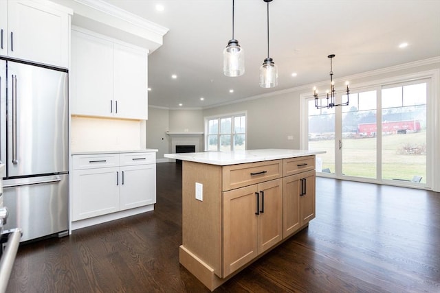 kitchen with stainless steel refrigerator, a center island, dark hardwood / wood-style flooring, decorative light fixtures, and white cabinets