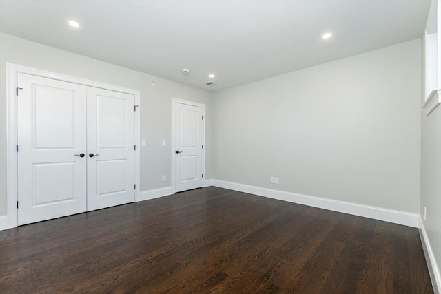 unfurnished bedroom with dark hardwood / wood-style flooring and a closet