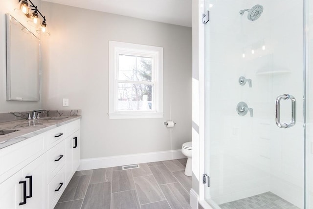 bathroom with an enclosed shower, vanity, and toilet