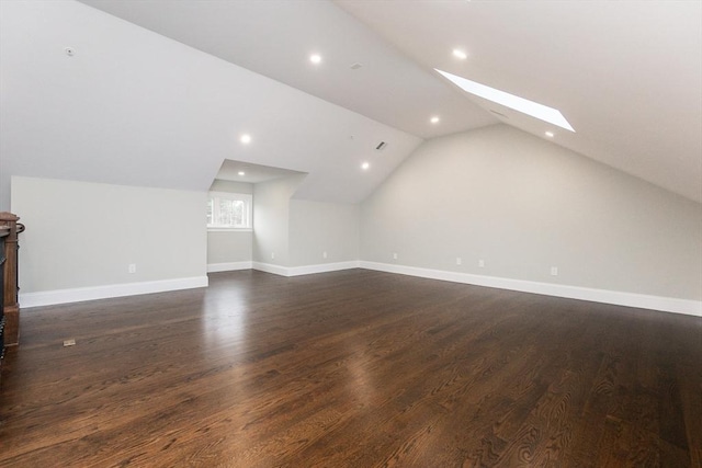 additional living space with lofted ceiling with skylight and dark wood-type flooring