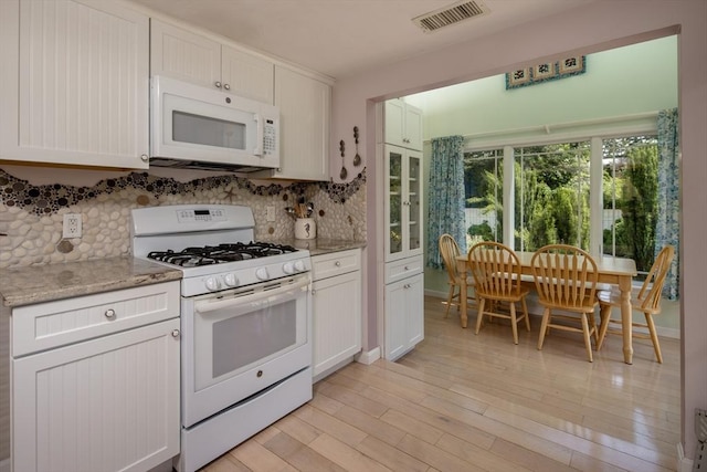 kitchen with white cabinetry, light stone counters, white appliances, and decorative backsplash