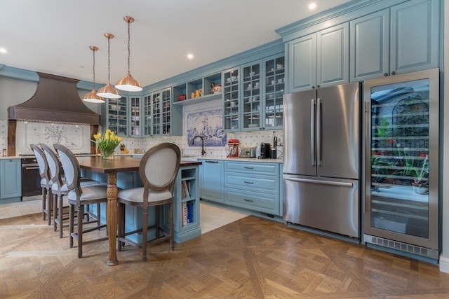 kitchen featuring premium range hood, a center island, decorative light fixtures, light parquet floors, and stainless steel refrigerator