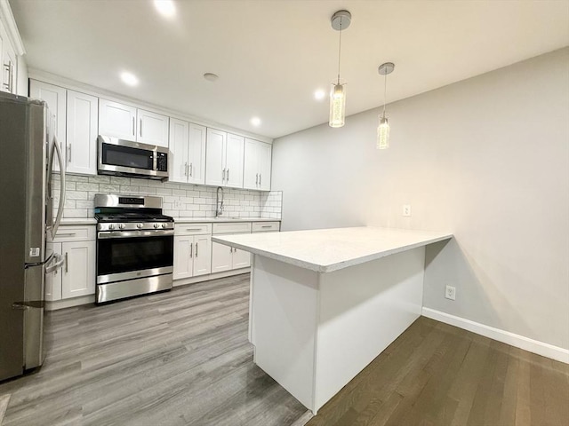 135 Granite Ave Unit 23, Boston, MA 02124 - kitchen with appliances with stainless steel finishes, decorative backsplash, a peninsula, white cabinetry, and light countertops