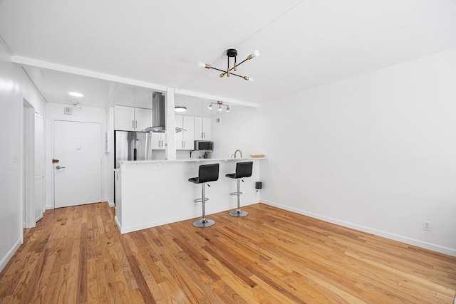99 Pond Ave Unit 202, Brookline, MA 02445 - kitchen featuring exhaust hood, stainless steel appliances, a breakfast bar, a chandelier, and light countertops