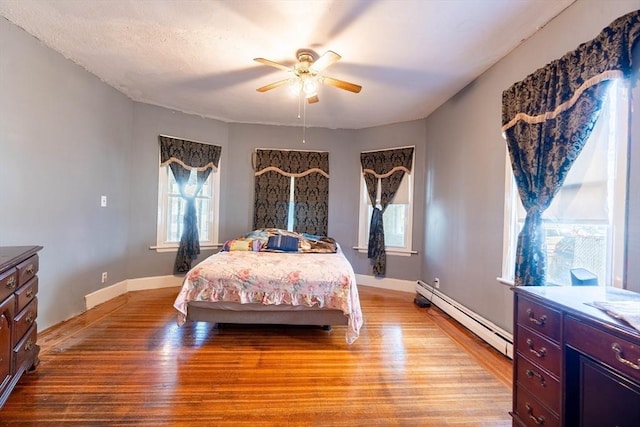 bedroom with light hardwood / wood-style flooring, ceiling fan, and baseboard heating