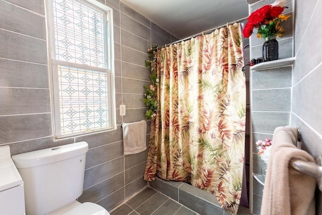 bathroom with curtained shower, tile walls, and toilet