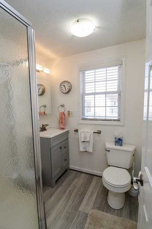 full bathroom featuring vanity, toilet, a shower stall, and wood finished floors