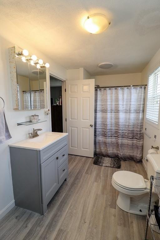 full bath featuring toilet, curtained shower, wood finished floors, and vanity
