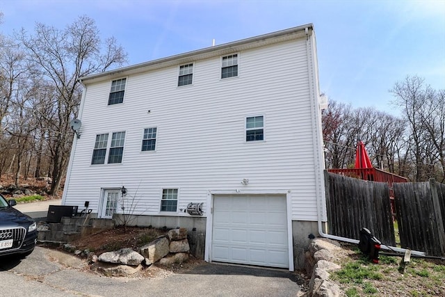 exterior space featuring an attached garage, fence, and aphalt driveway