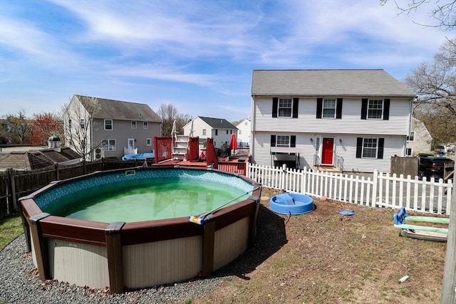 view of pool with a residential view, fence, and a jacuzzi