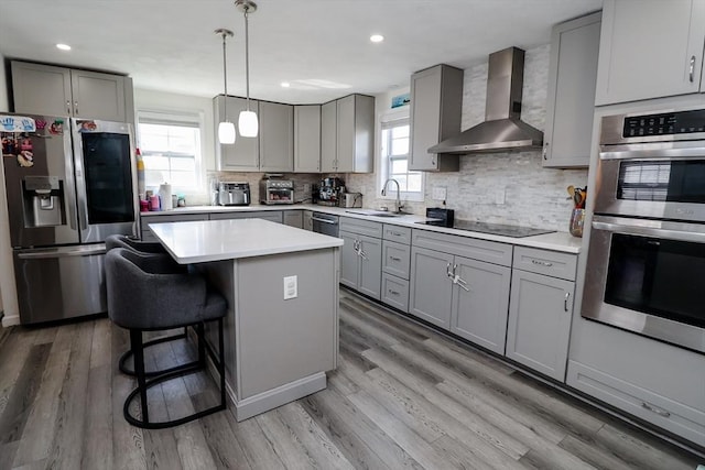 kitchen featuring wall chimney exhaust hood, gray cabinets, and appliances with stainless steel finishes