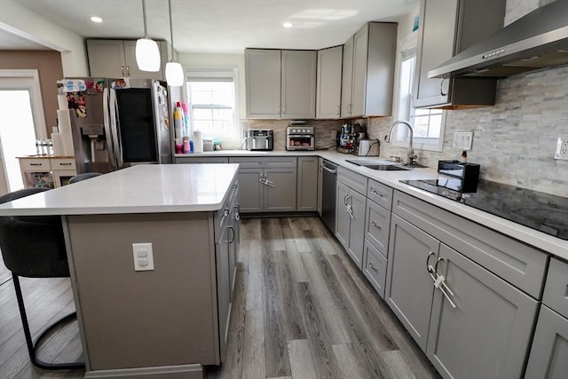 kitchen with a sink, a kitchen breakfast bar, extractor fan, appliances with stainless steel finishes, and gray cabinets
