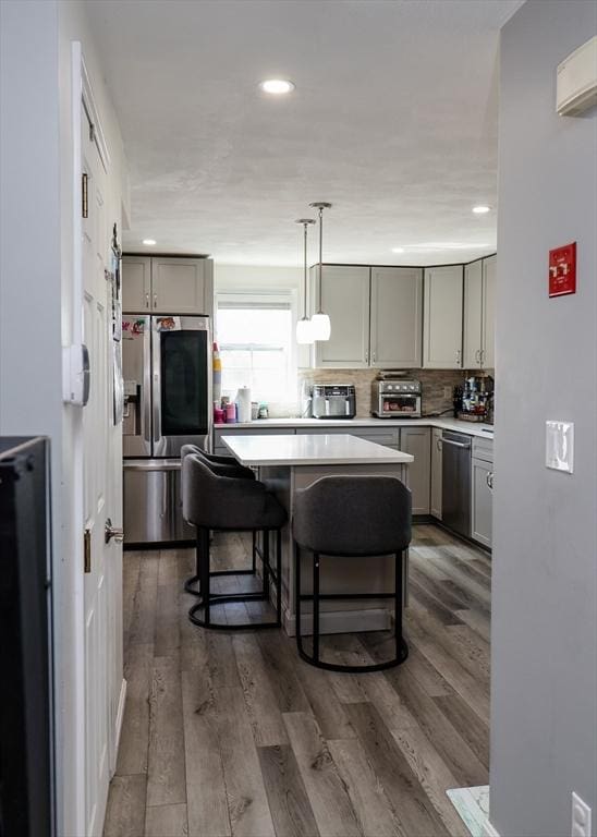 kitchen featuring stainless steel appliances, gray cabinets, a breakfast bar area, light countertops, and a kitchen island