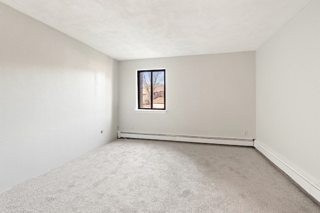 carpeted spare room with a baseboard heating unit