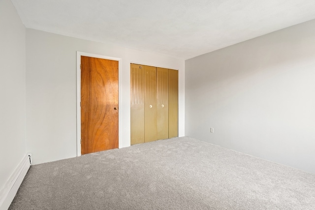 unfurnished bedroom featuring carpet flooring, a baseboard heating unit, and multiple closets