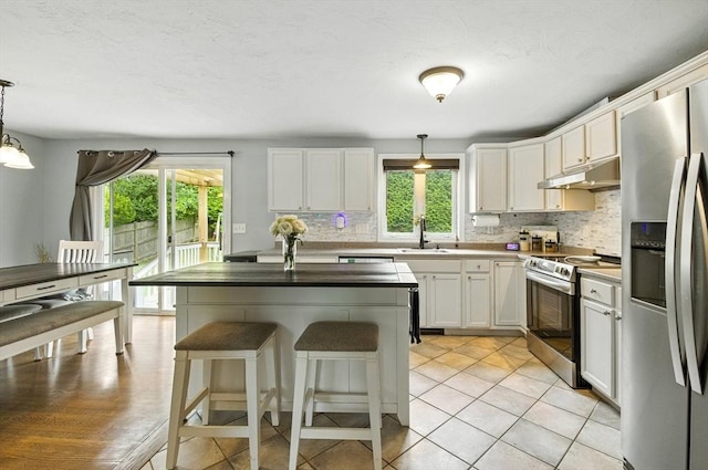 1 Cherry Tree Ln, Plainville, MA 02762 - kitchen with appliances with stainless steel finishes, under cabinet range hood, tasteful backsplash, a kitchen breakfast bar, and white cabinets