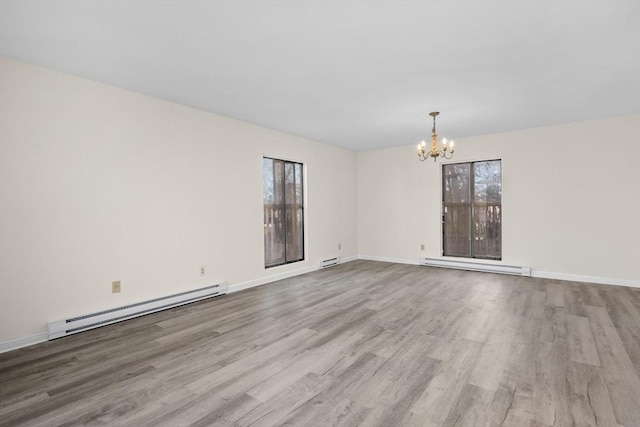 spare room featuring light wood-type flooring, baseboard heating, and a notable chandelier