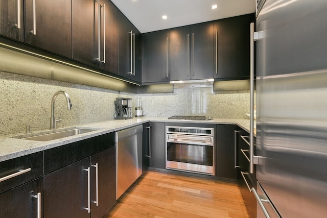 kitchen featuring light stone countertops, appliances with stainless steel finishes, sink, and light hardwood / wood-style floors