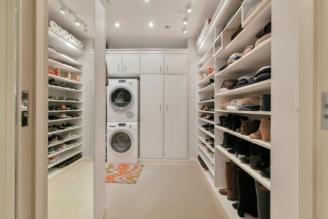 laundry room featuring cabinets, stacked washing maching and dryer, and light carpet