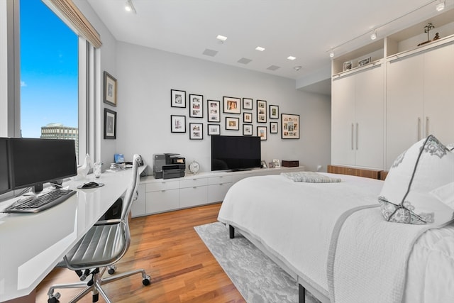 bedroom with track lighting and light hardwood / wood-style flooring