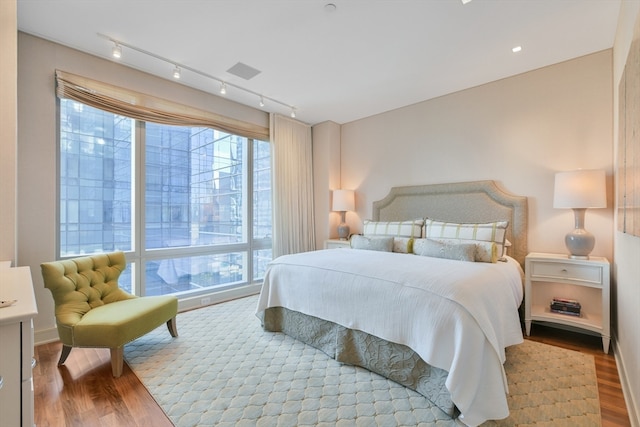 bedroom with light hardwood / wood-style floors and rail lighting