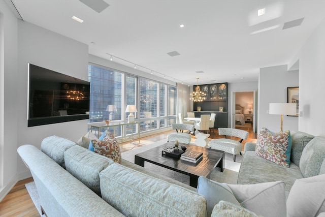 living room featuring light hardwood / wood-style flooring, rail lighting, and an inviting chandelier