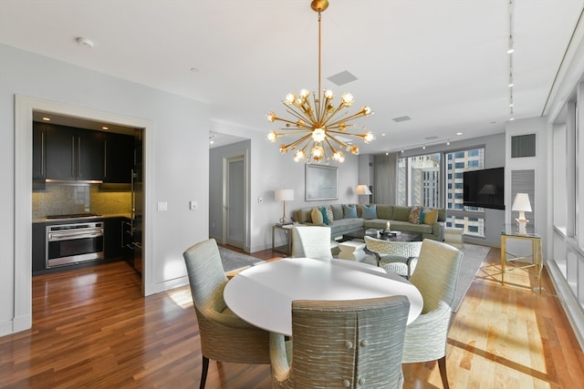 dining room featuring hardwood / wood-style flooring, track lighting, and an inviting chandelier