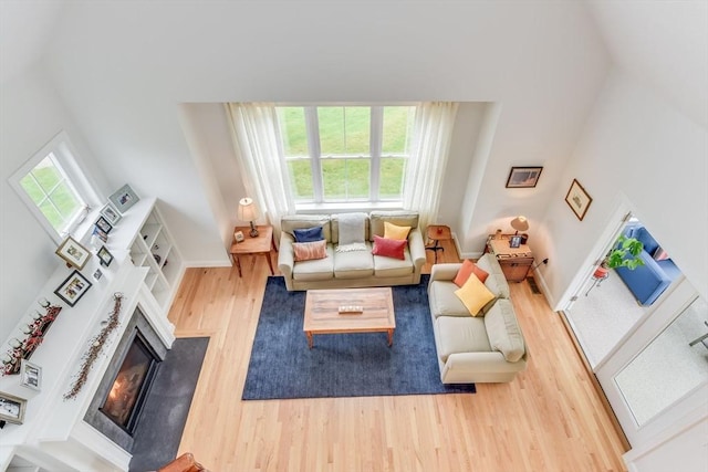 living area with baseboards, wood finished floors, and a glass covered fireplace