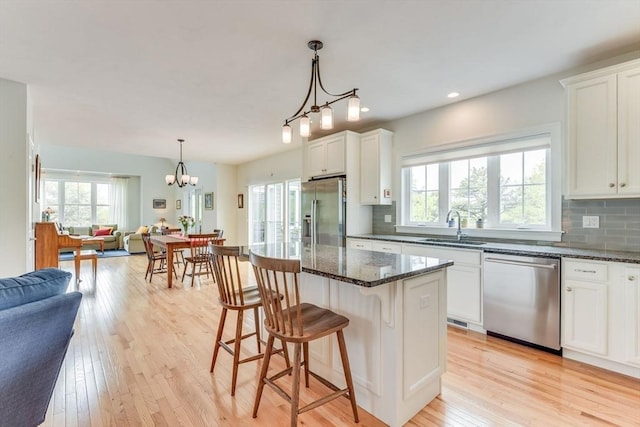 kitchen with light wood-style flooring, appliances with stainless steel finishes, open floor plan, and a sink