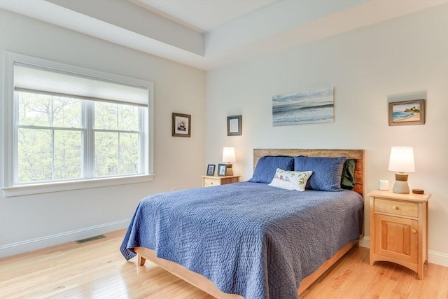 bedroom featuring light wood-style flooring, visible vents, and baseboards