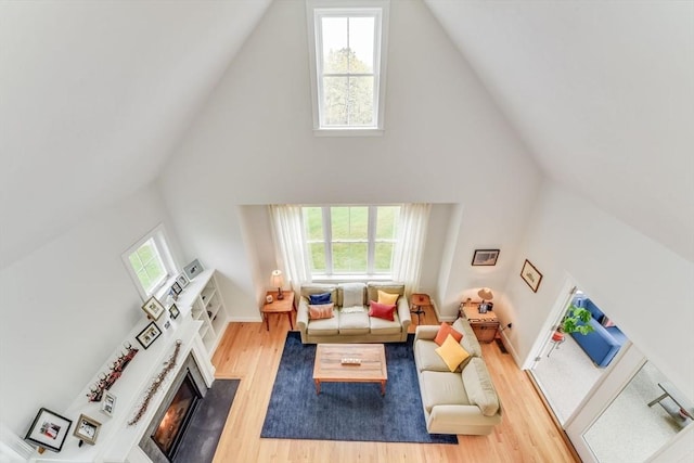 living room featuring a warm lit fireplace, plenty of natural light, and wood finished floors