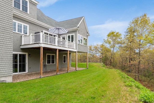 back of property featuring roof with shingles, a lawn, and a wooden deck