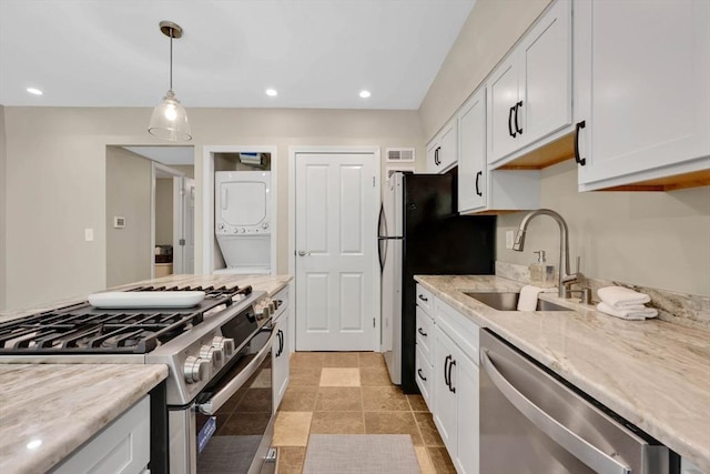 83 Jamestown Dr Unit 83, Springfield, MA 01108 - kitchen featuring appliances with stainless steel finishes, stacked washer and clothes dryer, a sink, white cabinets, and light stone countertops