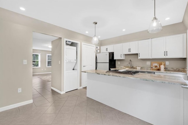 83 Jamestown Dr Unit 83, Springfield, MA 01108 - kitchen featuring freestanding refrigerator, stacked washer and clothes dryer, a sink, baseboards, and white cabinets