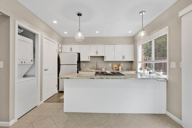 83 Jamestown Dr Unit 83, Springfield, MA 01108 - kitchen featuring freestanding refrigerator, stacked washer / dryer, light stone countertops, white cabinets, and stovetop
