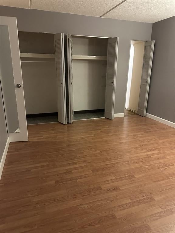 unfurnished bedroom featuring hardwood / wood-style floors, a textured ceiling, and two closets