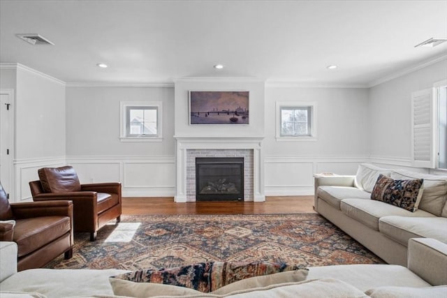 living room with dark wood-style floors, a fireplace, visible vents, and crown molding