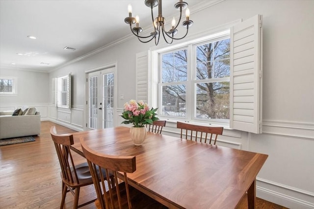 dining area with visible vents, a wainscoted wall, wood finished floors, crown molding, and french doors