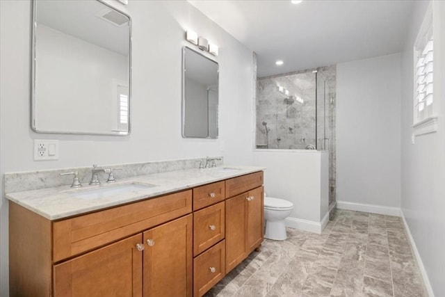 bathroom featuring double vanity, a stall shower, a sink, and baseboards