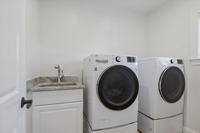 laundry area with washing machine and dryer, a sink, and cabinet space