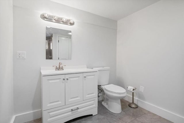 bathroom with toilet, vanity, and baseboards