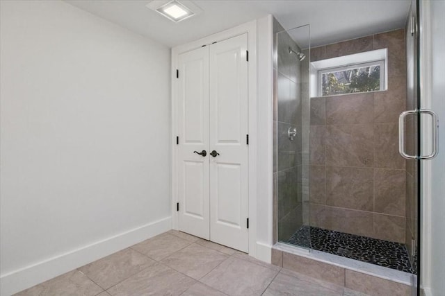 bathroom with baseboards, a tile shower, a closet, and tile patterned floors