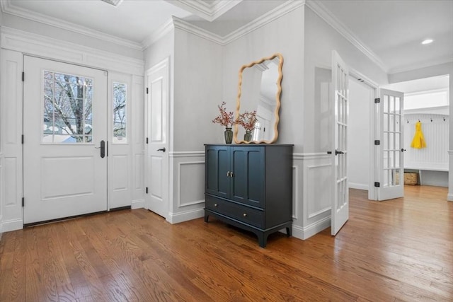 foyer featuring a decorative wall, crown molding, and wood finished floors