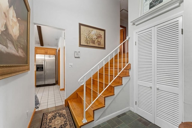 stairway featuring tile patterned floors, baseboards, and beam ceiling