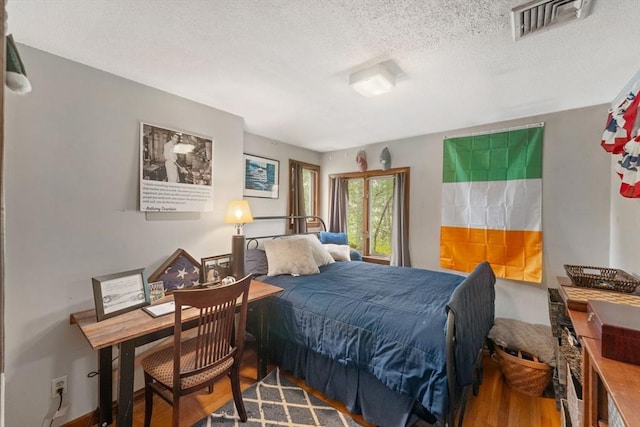 bedroom featuring visible vents, a textured ceiling, and wood finished floors
