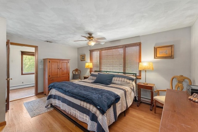 bedroom with a ceiling fan, baseboard heating, light wood-style flooring, baseboards, and a baseboard heating unit