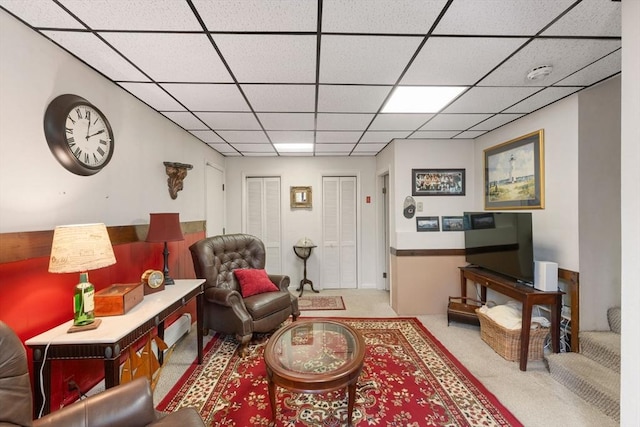 carpeted living area with a paneled ceiling