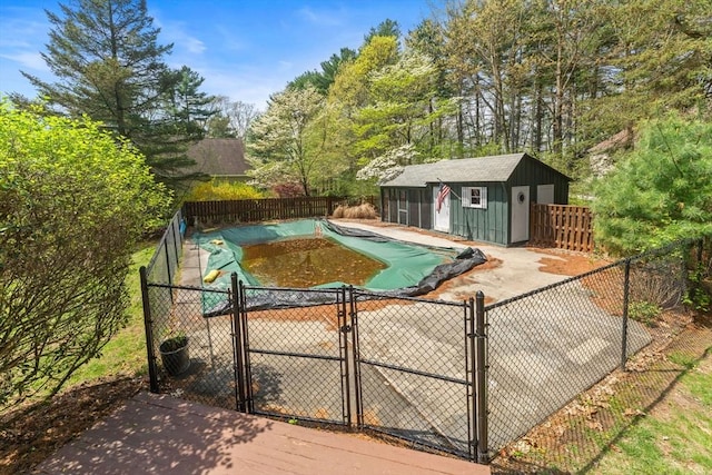 view of swimming pool featuring a gate, fence, a fenced in pool, and an outdoor structure